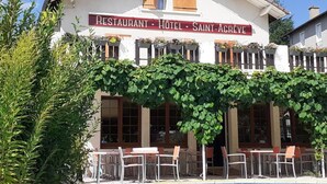 A building labeled 'LE 1050 RESTAURANT HOTEL SAINT-AGREVE' with outdoor seating and a vine-covered facade. - Logis Hotel le 1050 (Saint-Jeure-d'Andaure)