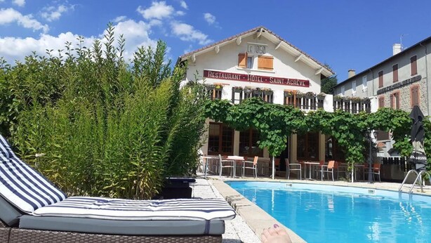 A hotel with a swimming pool, lounge chairs, and a sign indicating it is a restaurant, hotel, and Saint-Acreve. - Logis Hotel le 1050 (Saint-Jeure-d'Andaure)