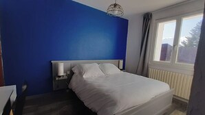 A bedroom with a bed, a bedside table, a lamp, and a window. - Logis Hotel le 1050 (Saint-Jeure-d'Andaure)