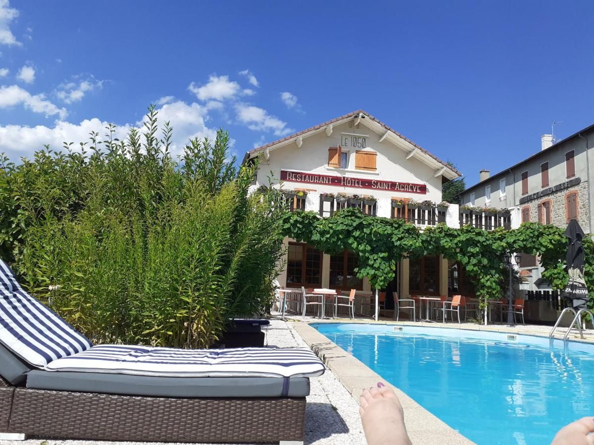 A hotel with a swimming pool, lounge chairs, and a sign indicating it is a restaurant, hotel, and Saint-Acreve.