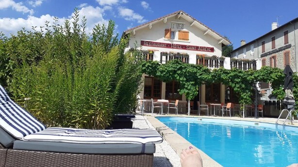 A hotel with a swimming pool, lounge chairs, and a sign indicating it is a restaurant, hotel, and Saint-Acreve. - Logis Hotel le 1050 (Saint-Jeure-d'Andaure)