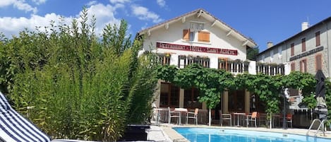 Un hotel con piscina, sillones de descanso y un cartel que indica que es restaurante, hotel y Saint-Acreve.