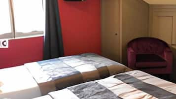 A room with two beds, a television on the wall, and a chair.