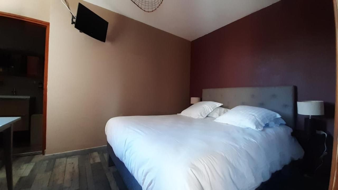Quarto com cama, televisão na parede e escrivaninha.