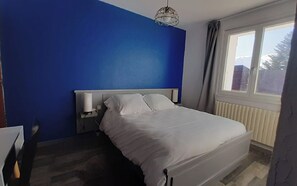 A bedroom with a bed, a bedside table, a lamp, and a window. - Logis Hotel le 1050 (Saint-Jeure-d'Andaure)