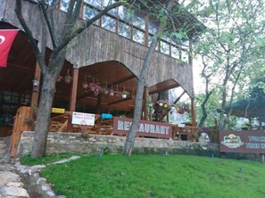 A rustic wooden building with a restaurant sign, a bike rental sign, and a sign for a Turkish Tree House. - Türkmen Ağaç Evleri (Kumluca)
