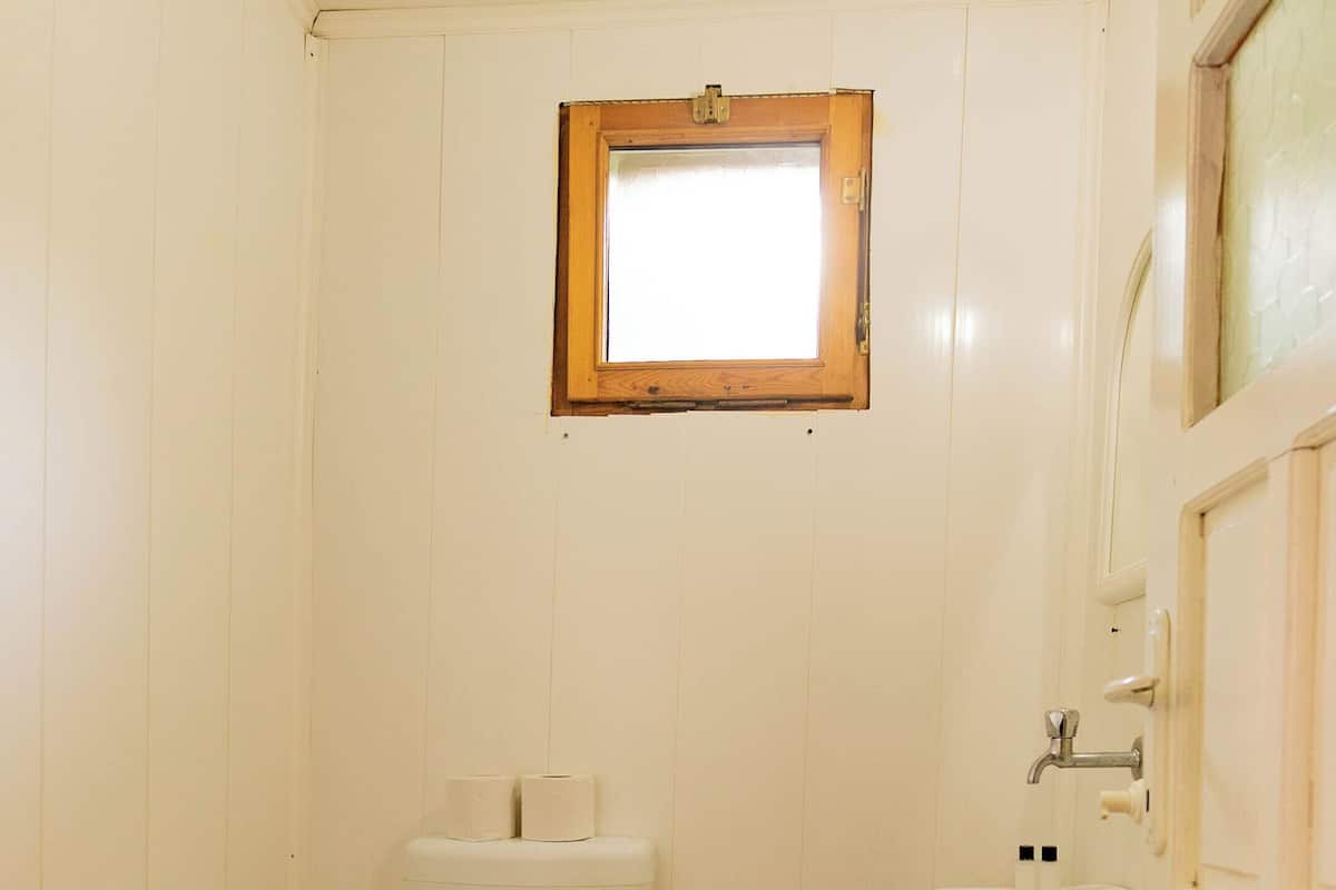 A small, white-walled bathroom with a toilet, sink, and a window above the toilet.