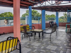 A covered outdoor seating area with metal chairs and a table, surrounded by blue railings and pillars. - Vaccinated Staff - 868 Solanos Transient House (Pasay)
