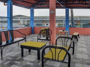 An outdoor seating area with metal chairs and tables, a tiled floor, and a view of a building in the background. - Vaccinated Staff - 868 Solanos Transient House (Pasay)