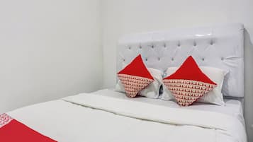 A bed with a white headboard and two red pillows with a repeated pattern.