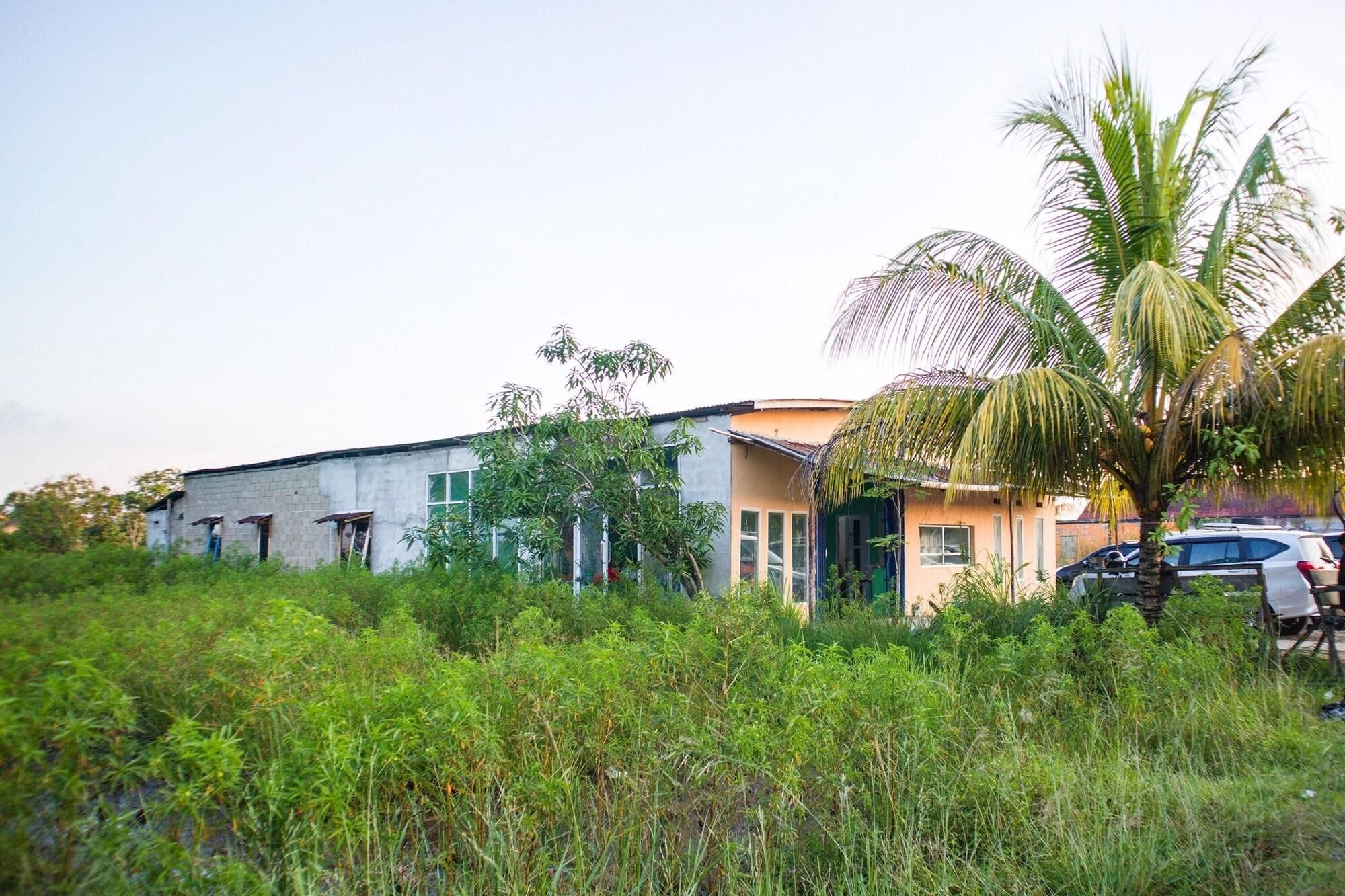 A building with a simple, unadorned exterior, surrounded by dense vegetation and a parked car.