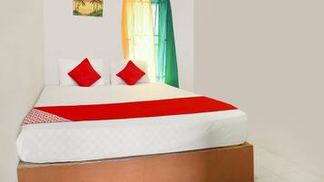 Una cama con colchón blanco, almohadas rojas y una colcha roja y blanca.