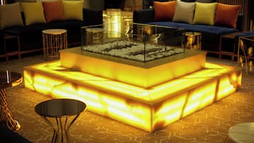 Un espace de vie moderne avec une table basse à plateau en verre, des canapés avec des coussins et un sol à motifs.