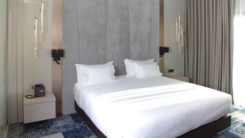 Une chambre d’hôtel avec un grand lit, des tables de chevet, un téléphone et un luminaire fixé au mur.