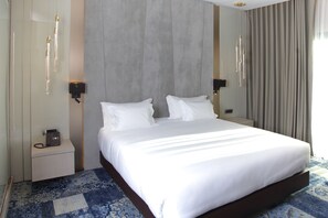 Ein Hotelzimmer mit einem großen Bett, Nachttischen, einem Telefon und einer Wandleuchte.