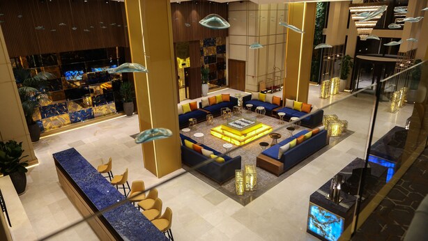 Un vestíbulo moderno con zona de estar, mostrador de recepción y pared decorativa con diseño geométrico.