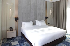 A hotel room with a large bed, bedside tables, a telephone, and a wall-mounted light fixture. - Oriental Palace (Taza)