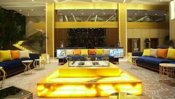 Eine geräumige Lobby mit einer zentralen Sitzecke, einer Treppe und einer großen Wand mit dekorativem Muster.