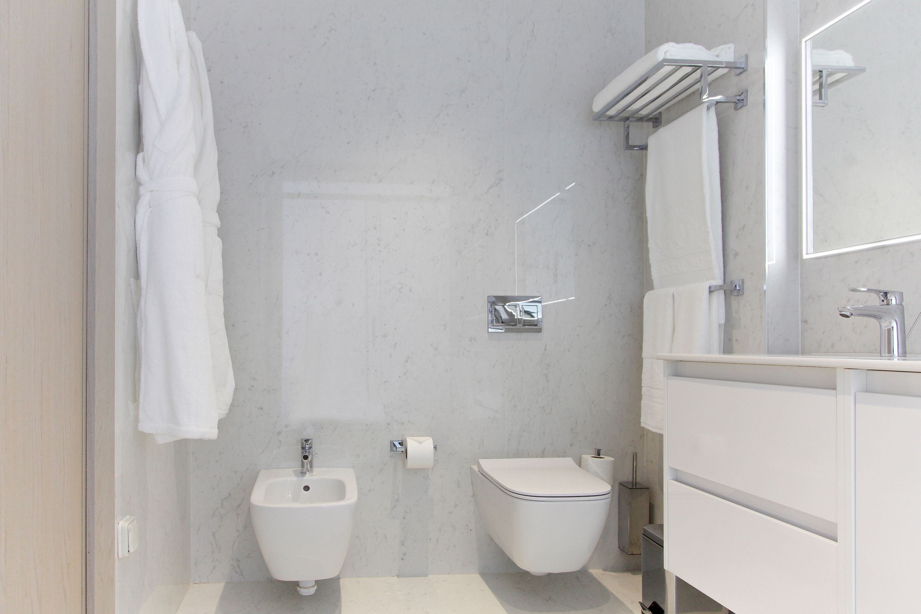 A modern bathroom with a bidet, toilet, and a large mirror.