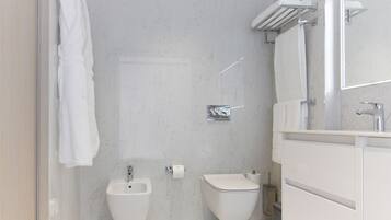 A modern bathroom with a bidet, toilet, and a large mirror.