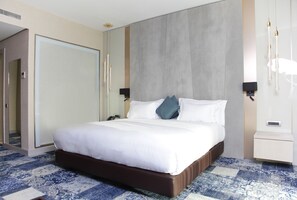 A hotel room with a large bed, a wardrobe, a bedside table, and a nightstand.