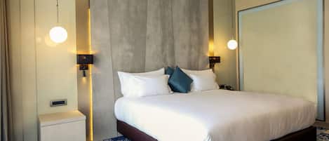 Une chambre d’hôtel moderne avec un grand lit, des lampes de chevet, une table de chevet et une moquette à motifs.