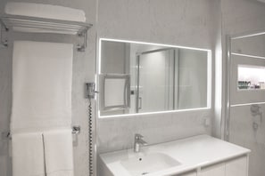 A bathroom with a large mirror, a sink, and a towel rack.