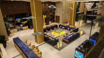 A modern lobby with a seating area, a reception desk, and a decorative wall with a geometric pattern.