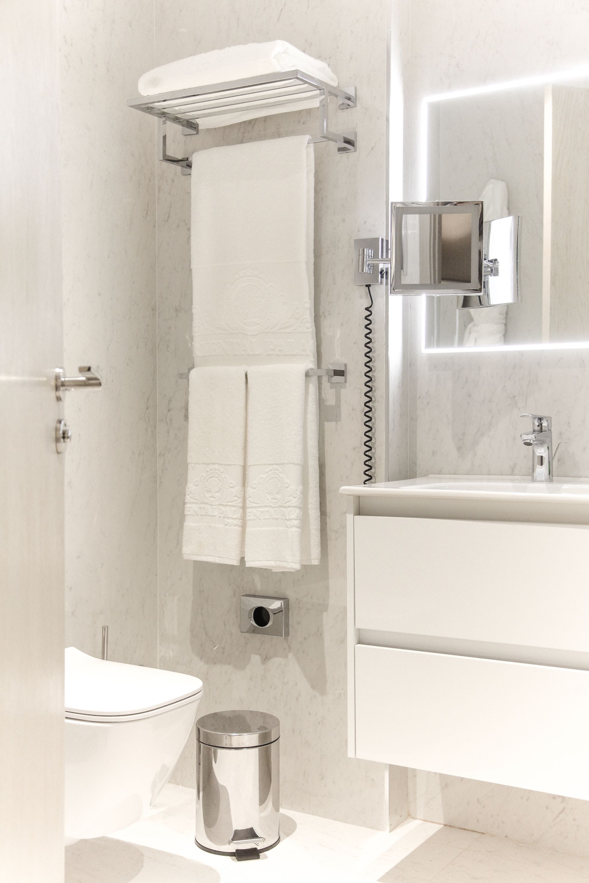 A modern bathroom with a toilet, a sink, a mirror, and a towel rack.