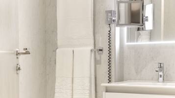 A modern bathroom with a toilet, a sink, a mirror, and a towel rack.