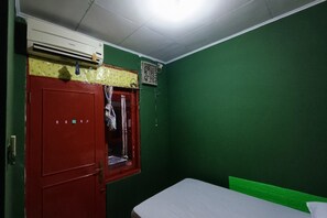 A room with a bed, a red door, an air conditioning unit, and a window with curtains. - OYO 91341 D'phoenix Anggrek Syariah Residence (Jakarta)