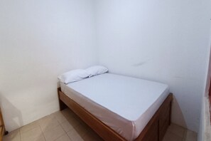 A small, single-bed room with a wooden frame and white bedding. - OYO 91341 D'phoenix Anggrek Syariah Residence (Jakarta)