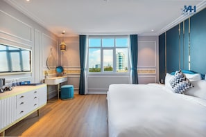 Ein Hotelzimmer mit Bett, Schreibtisch, Schminktisch, Spiegel, einem Fenster mit Vorhängen und Blick auf Gebäude.
