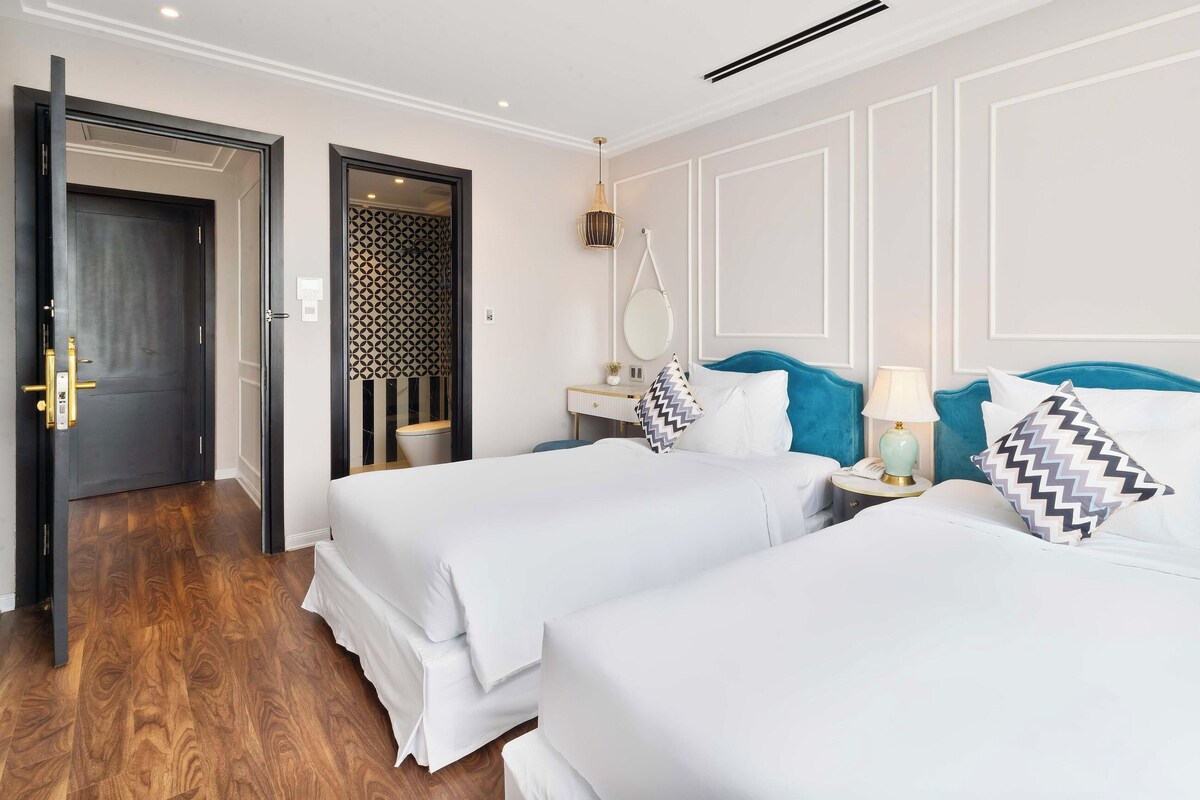Ein Hotelzimmer mit zwei Betten, einem Badezimmer und einer Tür.