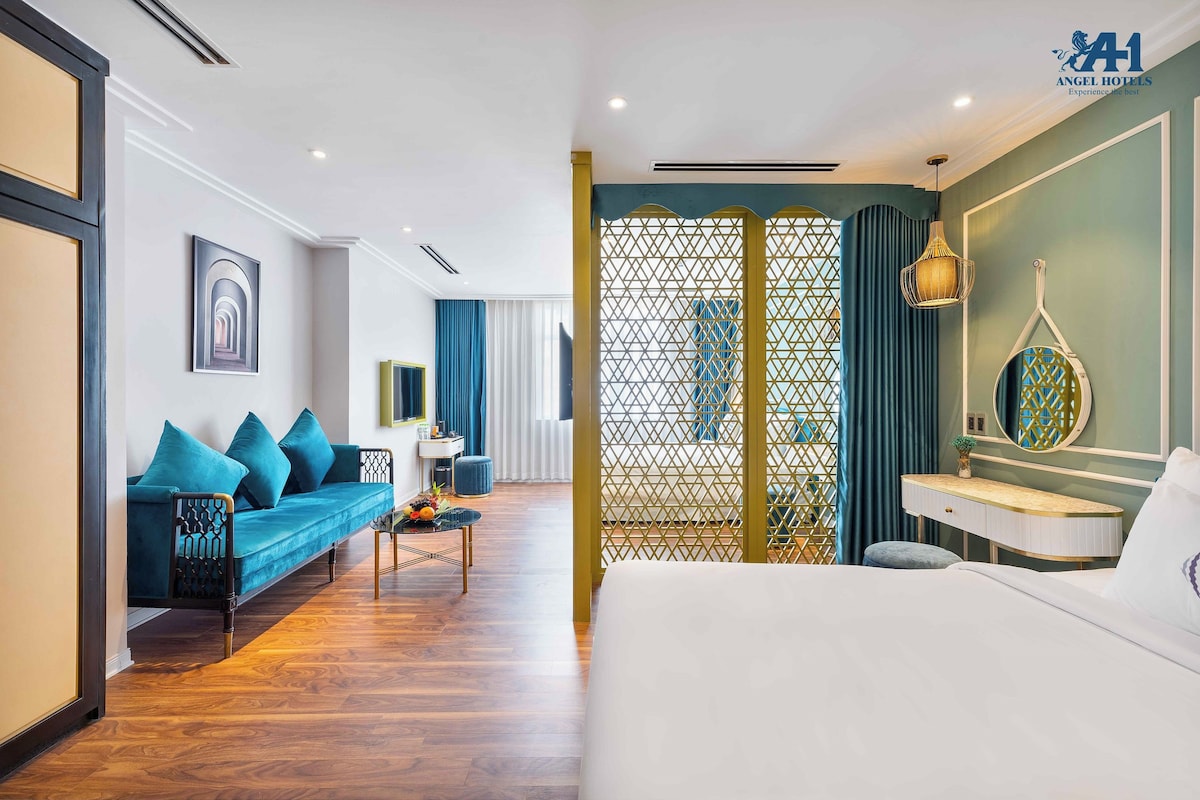 Ein Hotelzimmer mit Bett, einer Couch, einem Schreibtisch und einem dekorativen Raumteiler.
