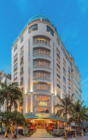Ein mehrstöckiges Hotel mit einer geschwungenen Fassade, Balkonen und einem Restaurant im Erdgeschoss.