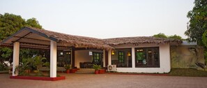 A building with a thatched roof, a covered entrance, and a mural on the wall. - Club Mahindra Gir (Mendarda)