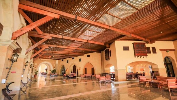 A spacious lobby with high ceilings, arched doorways, and a polished marble floor.