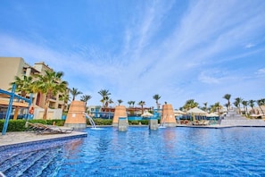 A swimming pool with lounge chairs, palm trees, and a clear sky. - Pickalbatros Oasis Hotel - Port Ghalib (El Quseir)