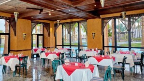 A restaurant with tables set for dining, large windows, and a wooden ceiling.