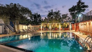 A swimming pool with lounge chairs and a covered seating area. - Club Mahindra Saj Mahabaleshwar (Mahabaleshwar)