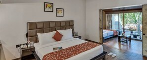 Hotelkamer met een groot bed, nachtkastje, raam met uitzicht en een deur naar een buitenruimte.
