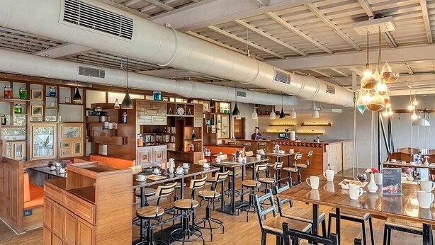 A café with wooden furniture, a bar area, and shelves with various items. - Club Mahindra Saj Mahabaleshwar (Mahabaleshwar)