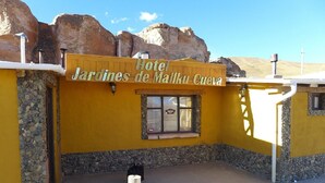 A yellow building with a sign reading 'Hotel Jardines de Malka Cuervo.' - Hotel Jardines de Mallku Cueva (Colcha K)