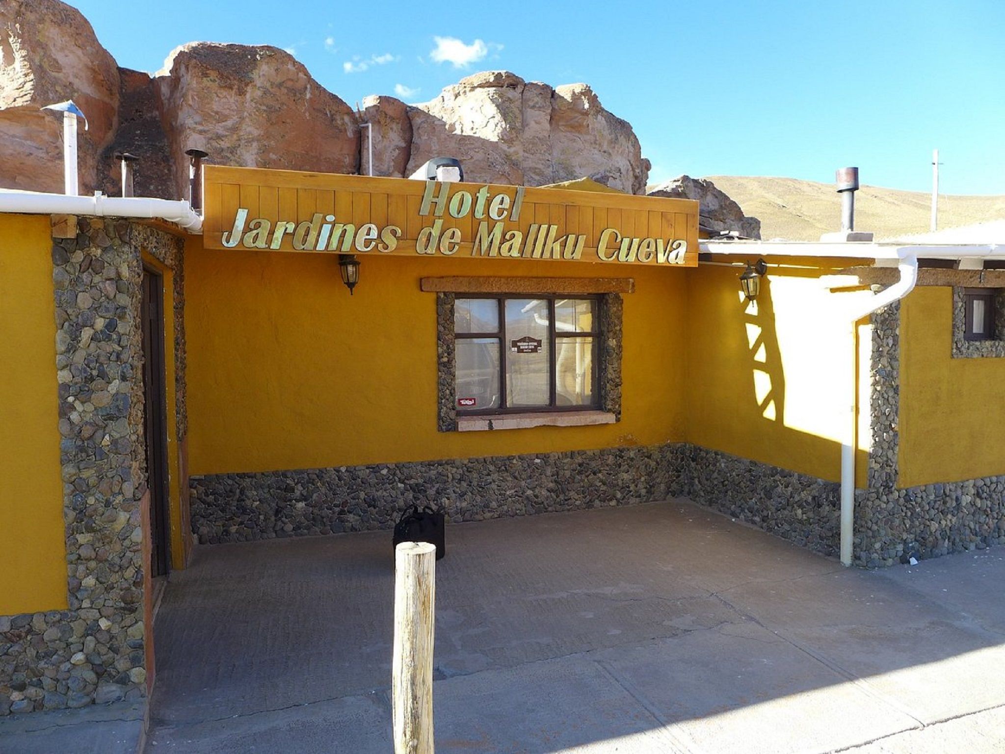 Un edificio amarillo con un letrero que dice 'Hotel Jardines de Malka Cuervo'.