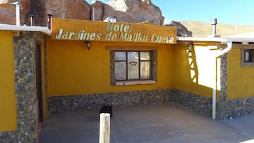 Un edificio amarillo con un letrero que dice 'Hotel Jardines de Malka Cuervo'.