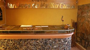 A reception desk with a stone base, a wooden sign above it, and a stone wall to the right. - Hotel Jardines de Mallku Cueva (Colcha K)