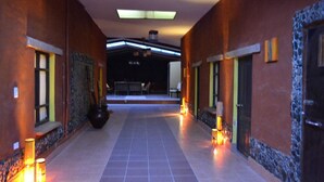 A corridor with tiled flooring, walls with textured patterns, and recessed lighting. - Hotel Jardines de Mallku Cueva (Colcha K)