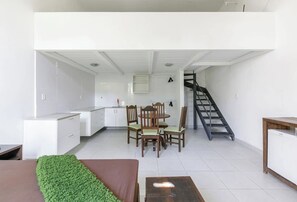 Un intérieur moderne comprenant un coin repas, une cuisine, un escalier et un canapé.