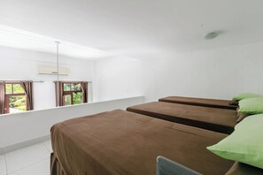 Une chambre avec deux lits, une fenêtre avec des rideaux, un luminaire au plafond et une vue sur la verdure.